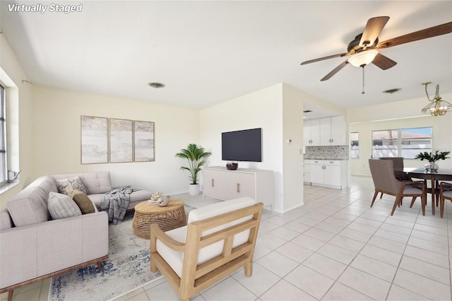 living room with ceiling fan with notable chandelier and light tile patterned flooring