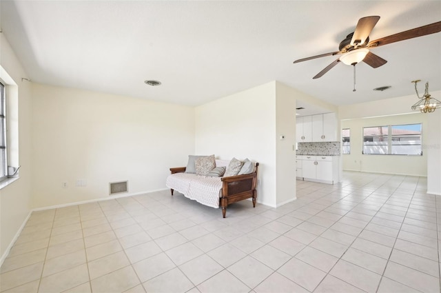 unfurnished room with ceiling fan with notable chandelier and light tile patterned flooring