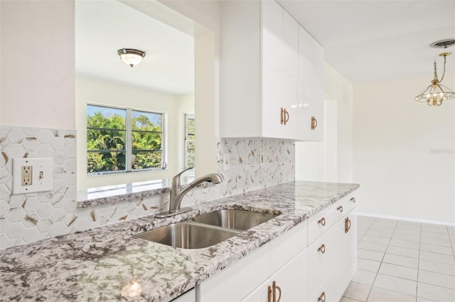 kitchen featuring a notable chandelier, backsplash, sink, and white cabinets