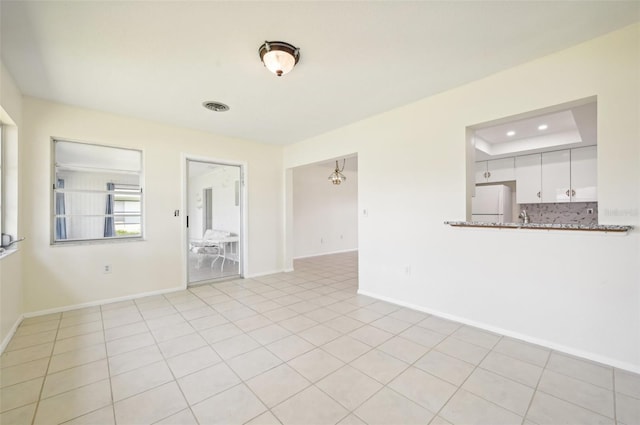 unfurnished living room with a raised ceiling and light tile patterned floors