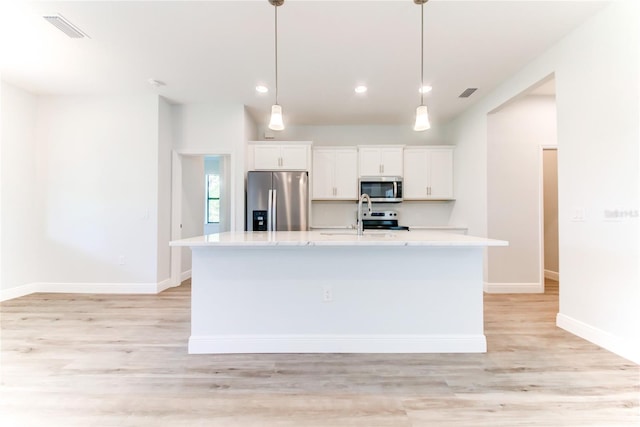 kitchen featuring white cabinetry, a center island with sink, appliances with stainless steel finishes, and hanging light fixtures