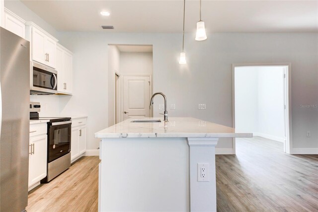 kitchen featuring stainless steel appliances, hanging light fixtures, a kitchen island with sink, and light wood-type flooring