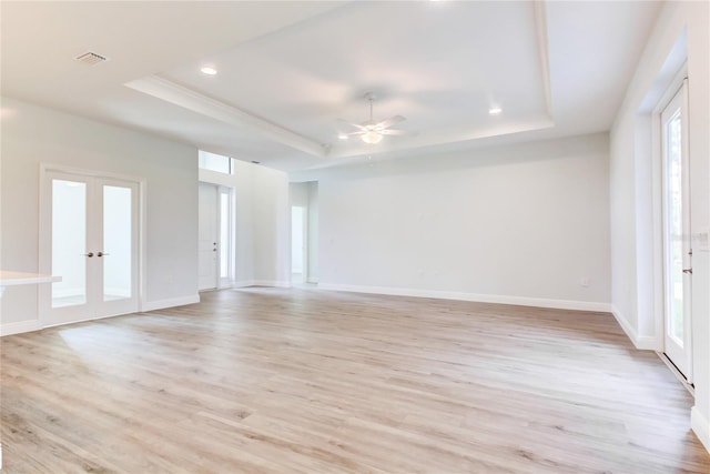 unfurnished room featuring ceiling fan, a tray ceiling, and light hardwood / wood-style flooring