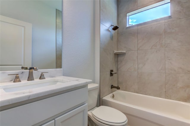 full bathroom featuring tiled shower / bath, vanity, and toilet