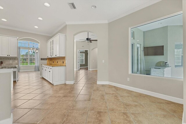 kitchen with white cabinetry, ceiling fan, backsplash, light tile patterned flooring, and ornamental molding