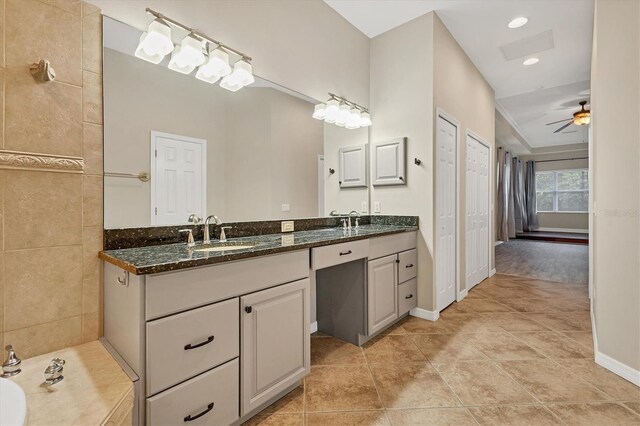 bathroom with tile patterned floors, a bathing tub, ceiling fan, and vanity