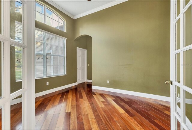 empty room with hardwood / wood-style flooring, a healthy amount of sunlight, crown molding, and french doors