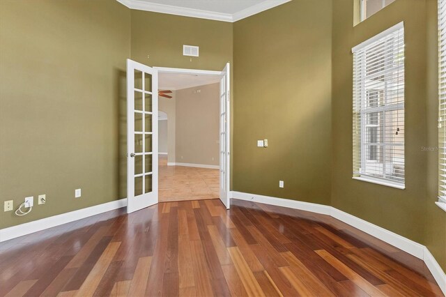 spare room with french doors, hardwood / wood-style flooring, plenty of natural light, and ornamental molding