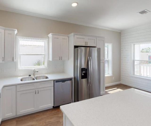 kitchen with appliances with stainless steel finishes, sink, white cabinetry, and a wealth of natural light