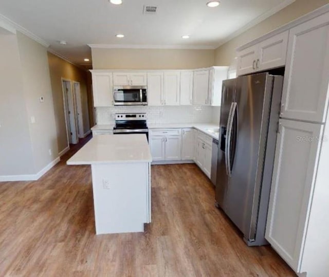 kitchen featuring white cabinets, tasteful backsplash, light hardwood / wood-style flooring, stainless steel appliances, and a center island