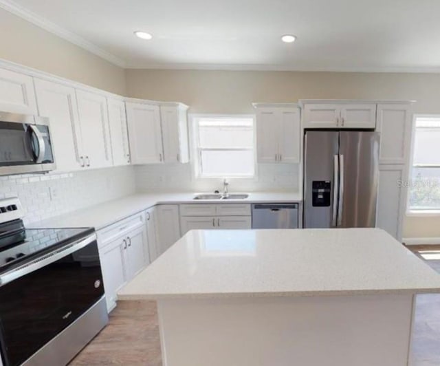 kitchen with appliances with stainless steel finishes, a center island, sink, and white cabinetry