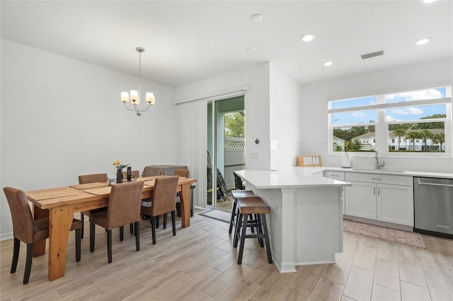 kitchen featuring pendant lighting, dishwasher, white cabinets, and a wealth of natural light