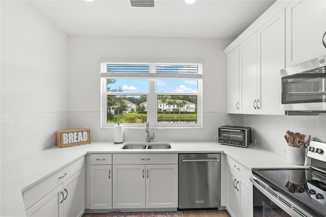 kitchen with white cabinetry, sink, stainless steel appliances, and tasteful backsplash