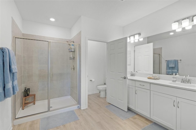 bathroom with hardwood / wood-style floors, vanity, toilet, and a shower with shower door