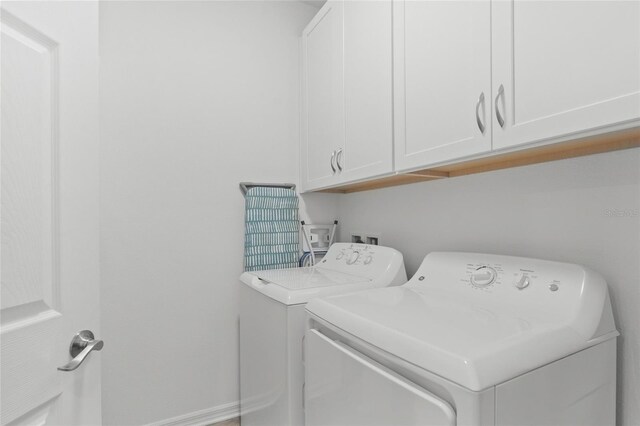 clothes washing area featuring washing machine and clothes dryer and cabinets