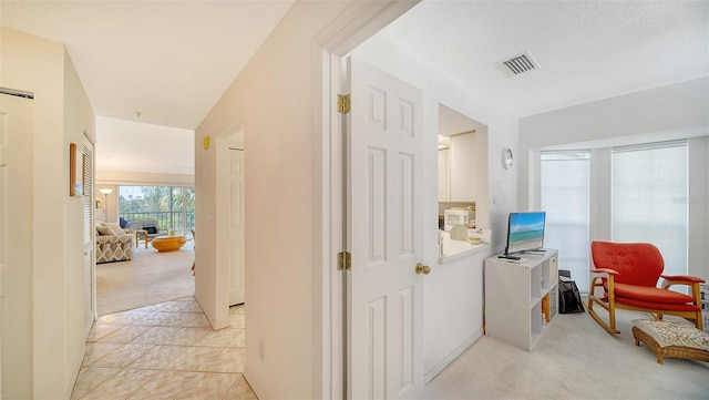 hallway with a textured ceiling and light carpet