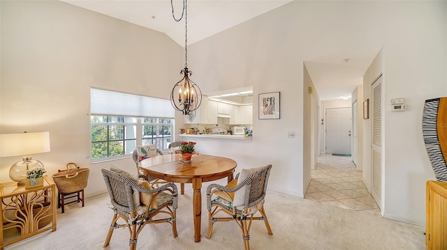 carpeted dining room featuring an inviting chandelier and high vaulted ceiling