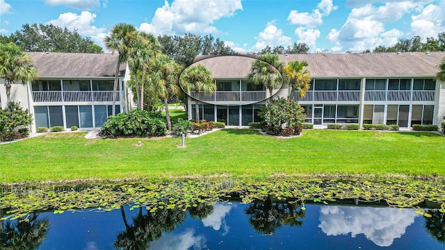 back of property featuring a yard, a water view, and a balcony