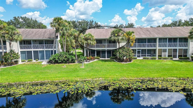 rear view of property featuring a lawn and a balcony