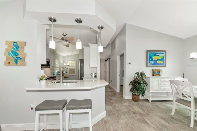 kitchen featuring hanging light fixtures, kitchen peninsula, white cabinetry, and sink