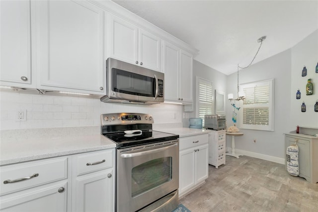 kitchen featuring pendant lighting, light stone counters, white cabinets, backsplash, and appliances with stainless steel finishes