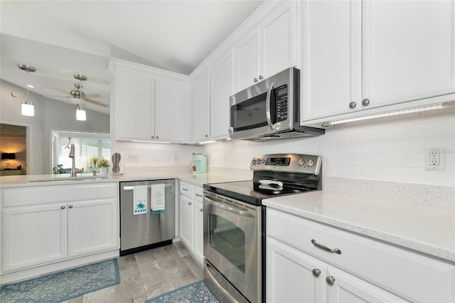 kitchen with vaulted ceiling, sink, stainless steel appliances, and white cabinets