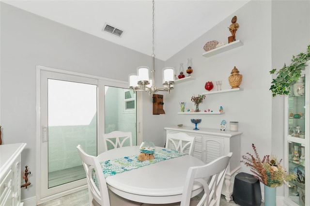 dining space with an inviting chandelier, light hardwood / wood-style floors, and vaulted ceiling