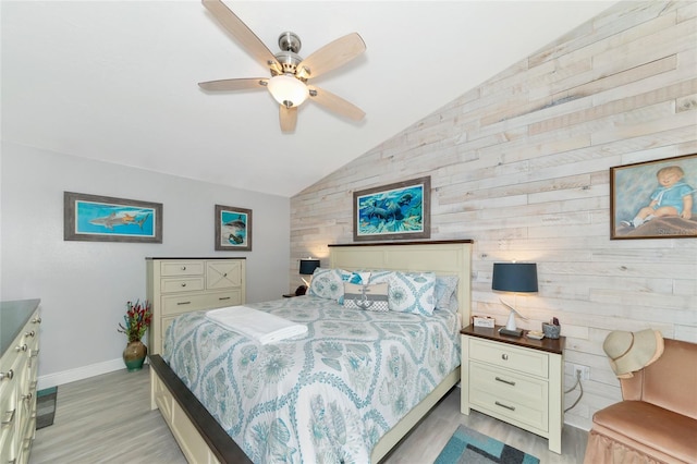 bedroom featuring ceiling fan, light hardwood / wood-style floors, wood walls, and vaulted ceiling