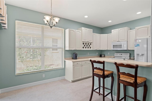 kitchen featuring a notable chandelier, white cabinets, white appliances, light tile patterned floors, and decorative light fixtures