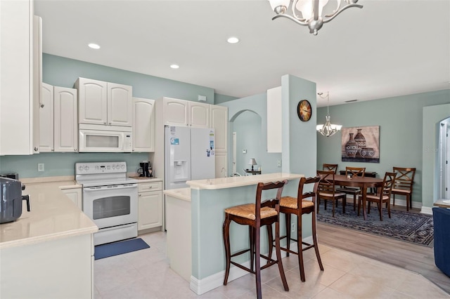 kitchen featuring light hardwood / wood-style floors, white appliances, white cabinetry, and pendant lighting