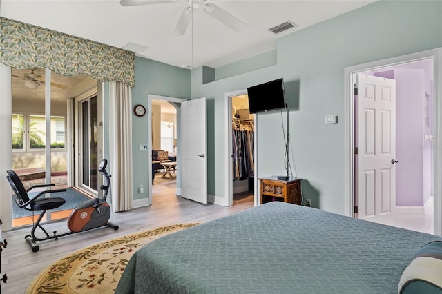 bedroom with wood-type flooring, a closet, a walk in closet, and ceiling fan