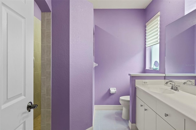 bathroom with tile patterned flooring, vanity, toilet, and tiled shower