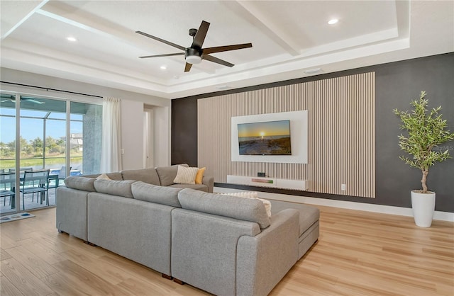 living room with a tray ceiling, light hardwood / wood-style floors, and ceiling fan