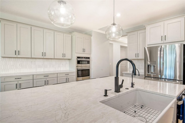 kitchen featuring sink, decorative light fixtures, backsplash, stainless steel appliances, and light stone countertops