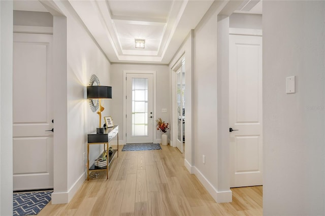 doorway featuring light hardwood / wood-style flooring and a tray ceiling