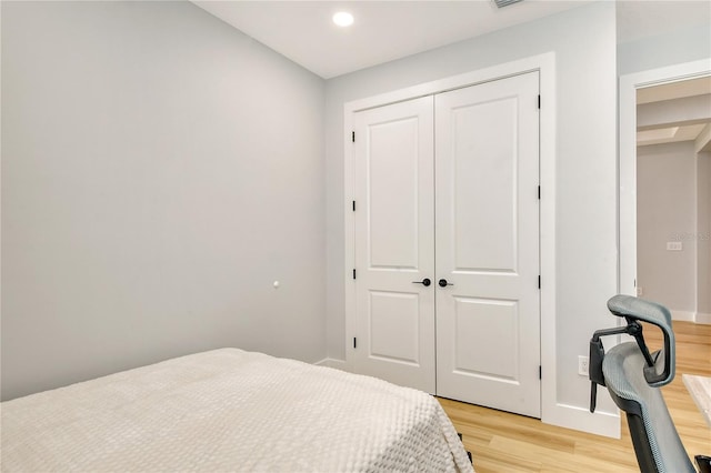 bedroom with light hardwood / wood-style floors and a closet