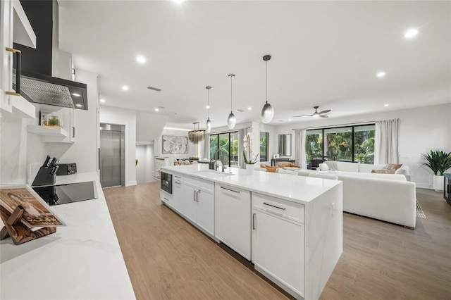 kitchen with black electric stovetop, extractor fan, a center island with sink, dishwasher, and white cabinetry