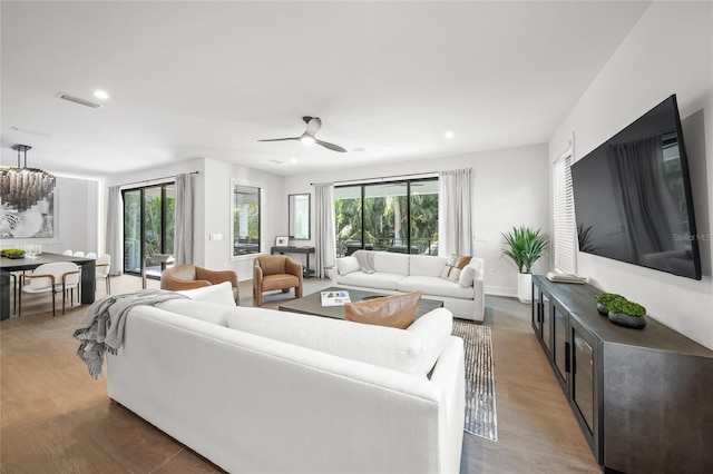 living room featuring wood-type flooring and ceiling fan with notable chandelier