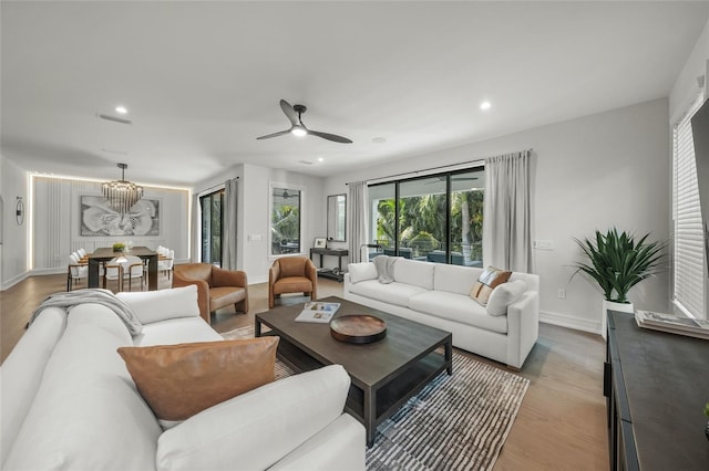 living room featuring wood-type flooring and ceiling fan with notable chandelier