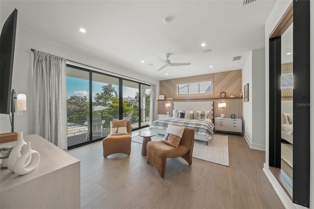 bedroom with ceiling fan, wood walls, access to exterior, and light hardwood / wood-style flooring