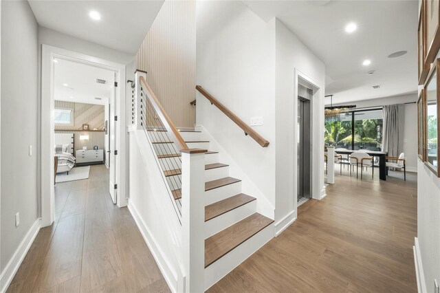 stairway with a chandelier and hardwood / wood-style floors