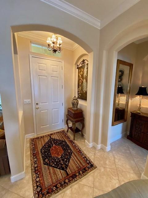 tiled foyer entrance with an inviting chandelier and crown molding