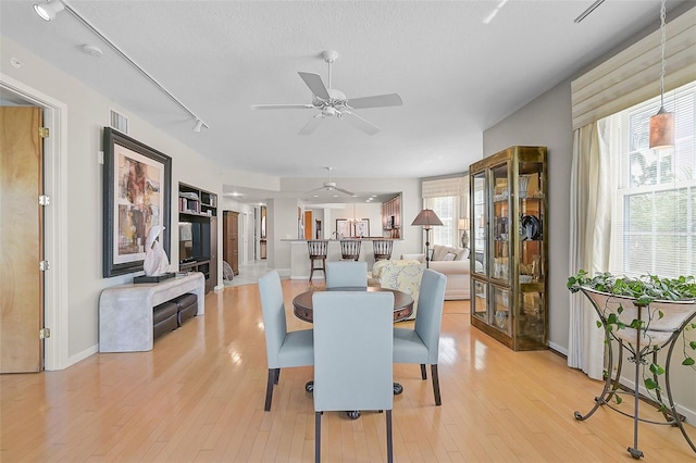 dining room featuring a textured ceiling, light hardwood / wood-style floors, and ceiling fan