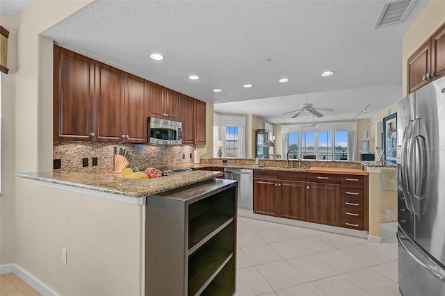 kitchen with sink, kitchen peninsula, decorative backsplash, stainless steel appliances, and ceiling fan