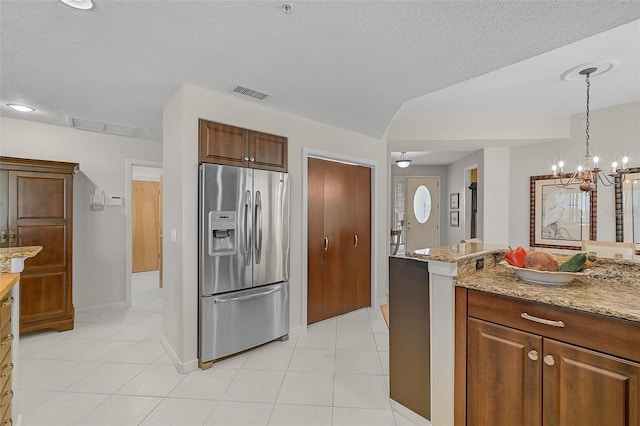 kitchen featuring hanging light fixtures, a textured ceiling, stainless steel fridge with ice dispenser, an inviting chandelier, and light stone countertops