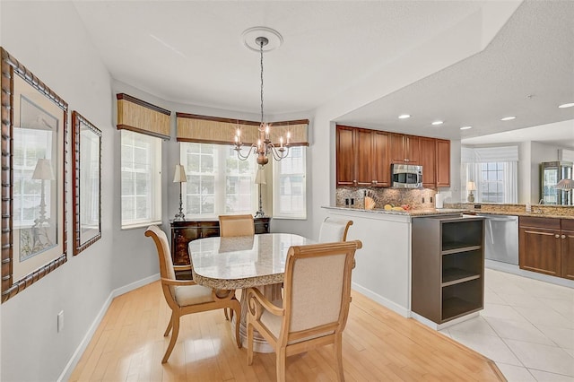 dining space featuring a notable chandelier, a textured ceiling, light hardwood / wood-style floors, and a wealth of natural light