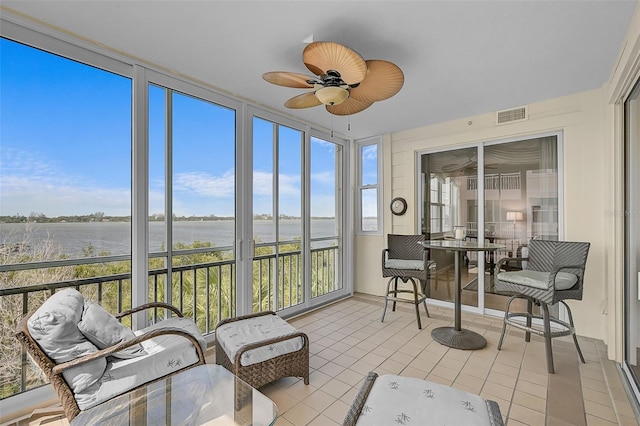 sunroom / solarium featuring a water view and ceiling fan