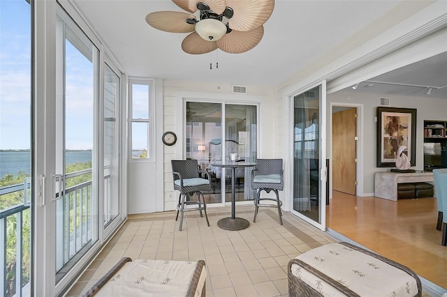 sunroom / solarium with a water view and ceiling fan