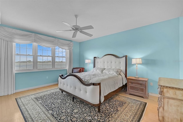 bedroom with light hardwood / wood-style flooring, a water view, and ceiling fan