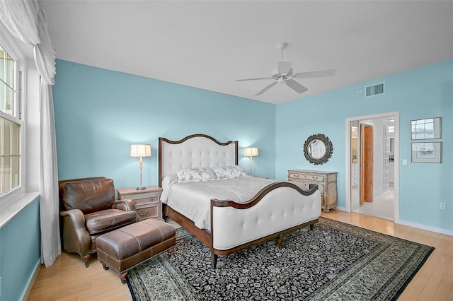 bedroom featuring light hardwood / wood-style floors, ensuite bath, and ceiling fan